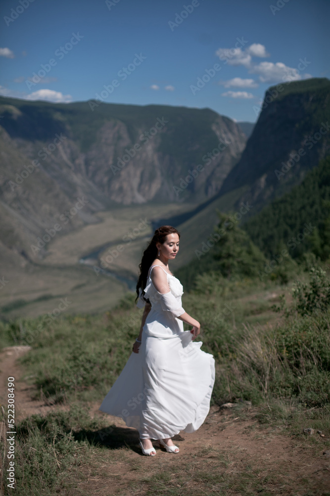 Bride in the mountains wedding image. A beautiful young woman in a wedding dress walks in the mountains. Bride in the mountains wedding image. A beautiful young woman in a wedding dress walks in the mountains.