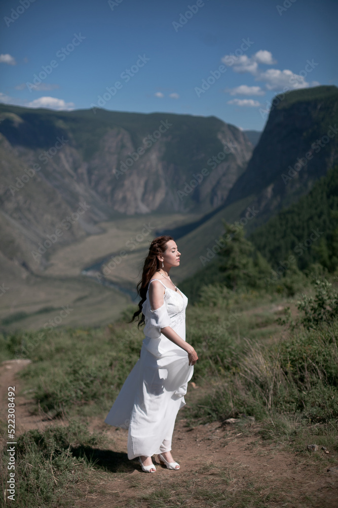 Bride in the mountains wedding image. A beautiful young woman in a wedding dress walks in the mountains.