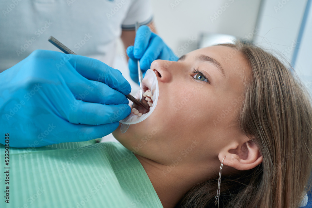 Fototapeta premium Professional pediatric dentist inspecting young patient teeth