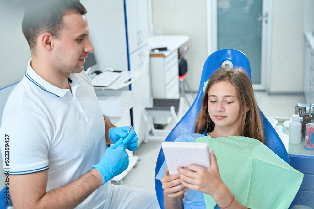 Teenage patient sitting in dentist office at initial consultation Teenage patient sitting in dentist office at initial consultation