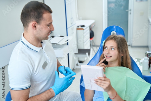 Teenage patient discussing dental problems with male doctor at consultation