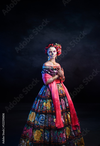 catrina woman dressed in a mexican chiapas costume with a black background pink rebozo and skull and bones makeup on her hands © ClicksdeMexico