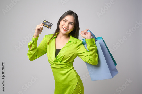 Beautiful woman holding credit card and shopping bag over white background studio, shopping and finance concept.
