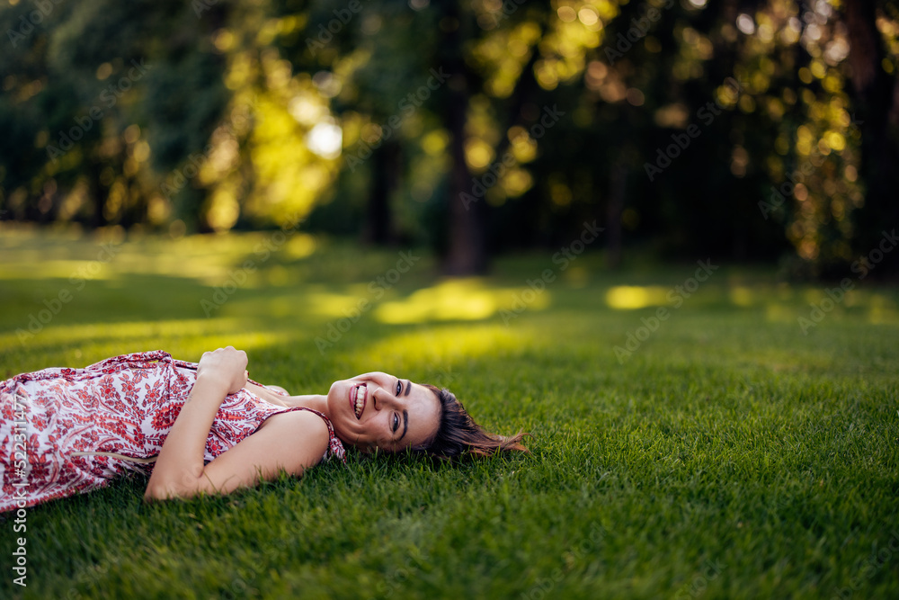 Smiling female laying on the grass alone smiling at the camera Stock Smiling female laying on the grass alone smiling at the camera Stock