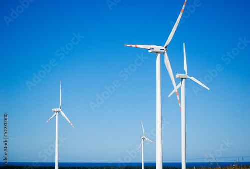 Windmill for electric power production against blue sky.