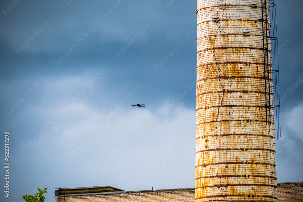 The drone flies near the ruins and the high water tower. Against the background of the summer sky with clouds.
