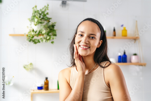 Portrait of young smiling hispanic woman with cosmetics on background. Wellness, positivity, skin care