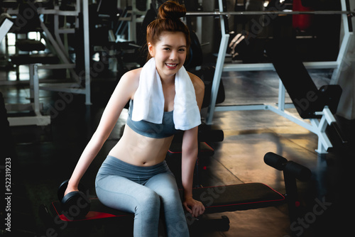 Young healthy Asian woman workout with weight lifting in the gym.