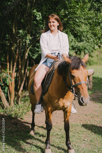 Beautiful woman rides a horse. Woman is riding a horse. Horse riding training for woman. Controlling the horse with the reins