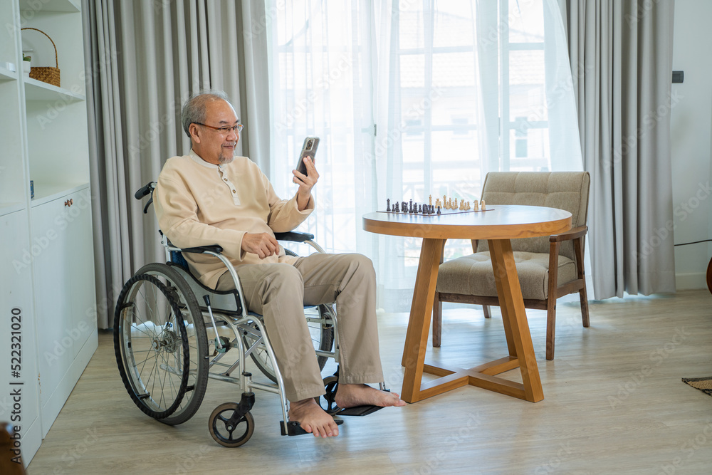 Senior man sitting on wheelchair and talking to relatives on video call conference in living room,Father using online video conference to start remote discussion with family. Senior man sitting on wheelchair and talking to relatives on video call conference in living room,Father using online video conference to start remote discussion with family.