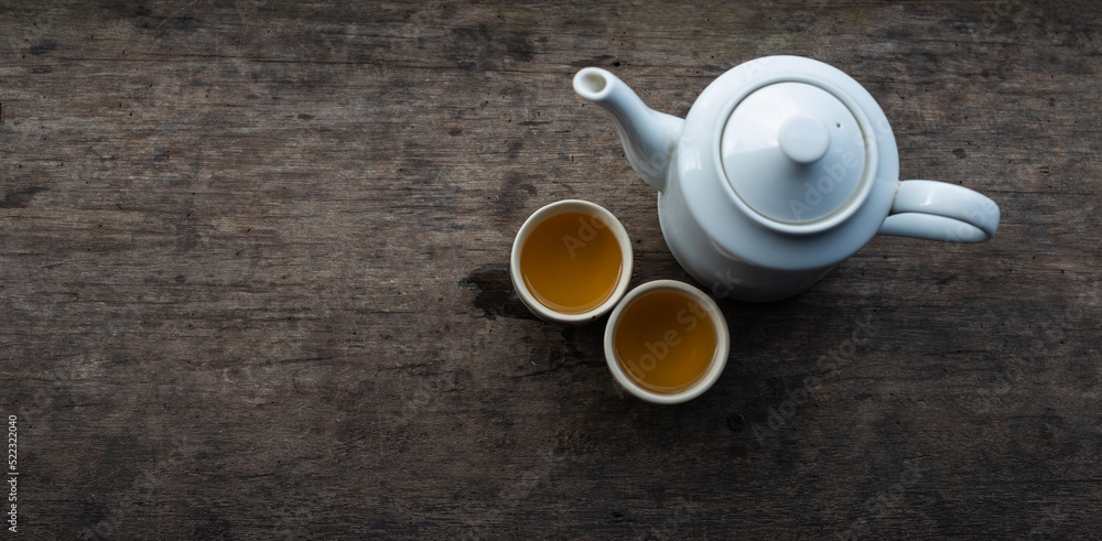 Top view of a white ceramic teapot set on a vintage colored wooden table. Top view of a white ceramic teapot set on a vintage colored wooden table.