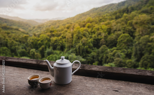 White ceramic teapot set on the table with natural mountain view in the morning.