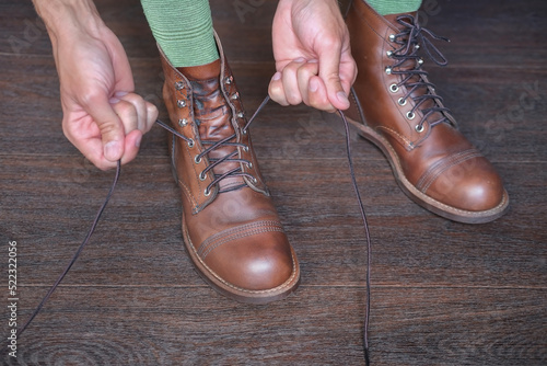 man in stylish leather shoes boot tying shoelaces close-up
