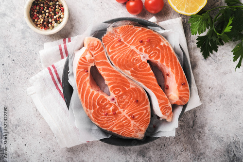 Salmon. Raw salmon steak. Fresh raw salmon fish with cooking ingredients, herbs and lemon prepared for grilled baking on light grey background. Healthy food. Top view. Copy space.