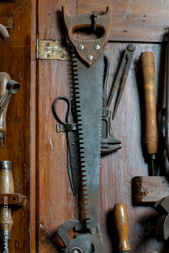 Old handsaw with other tools on wood photo