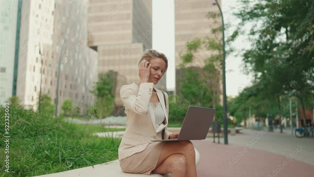 Businesswoman with blond hair wearing beige suit is using pc laptop outside Businesswoman with blond hair wearing beige suit is using pc laptop outside