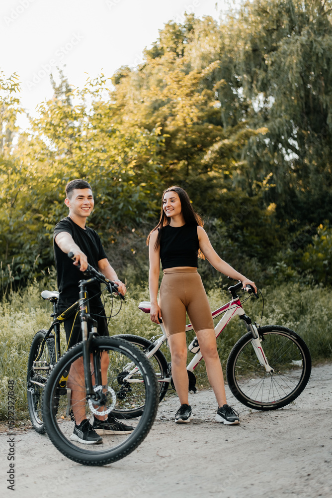 Cheerful young couple with bikes outdoors.