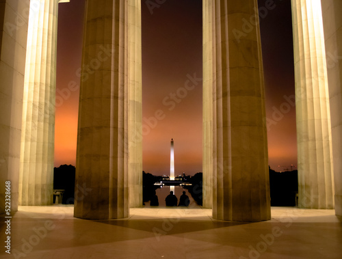 View of the Washington Monument from the Lincoln Memorial at midnight with three people sitting in the lobby, Washington D.C., USA