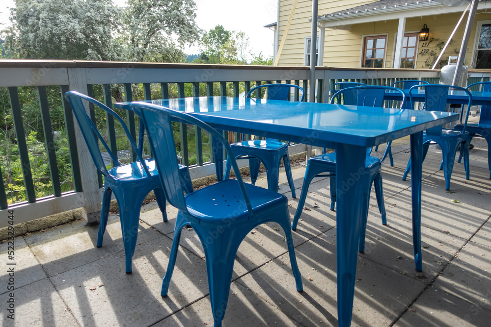 Colorful view of bright blue chairs gathered around a blue table on an outdoor patio at a restaurant Colorful view of bright blue chairs gathered around a blue table on an outdoor patio at a restaurant