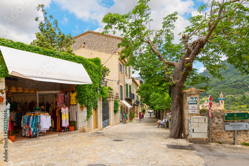 A picturesque street of shops and cafes in the medieval village of Valldemossa, Spain, on the Mediterranean island of Mallorca.	 photo