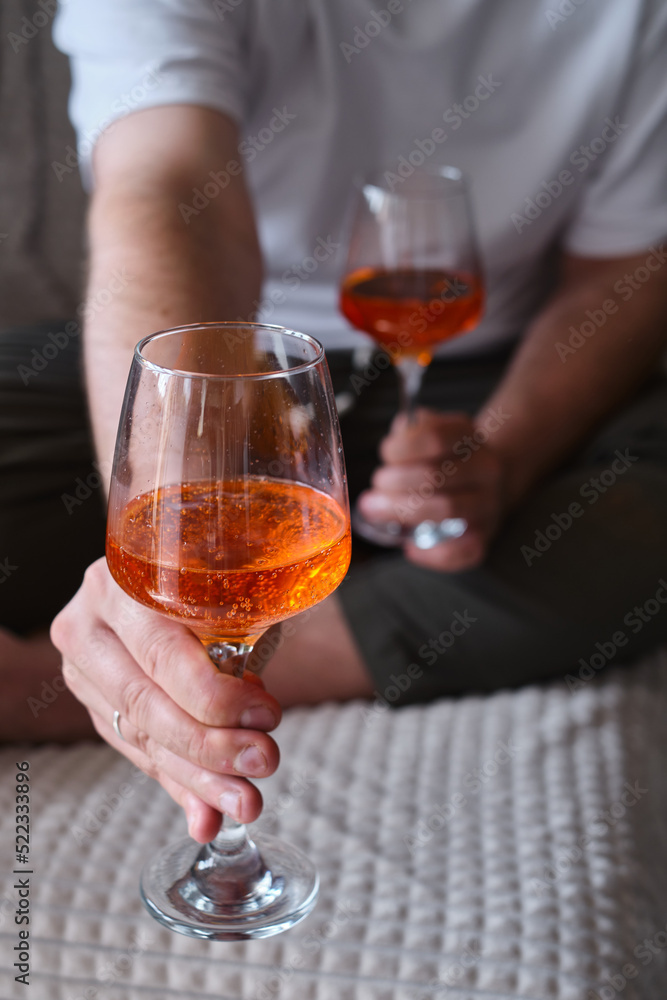 A glass of wine, aperol in the hands of a man resting at home Tasting alcoholic beverages. Romantic evening aperitif. Close-up of a glass of wine. Enjoy the moment