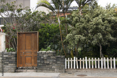 Puerta de madera color marr  n junto a un cerco de piedras.