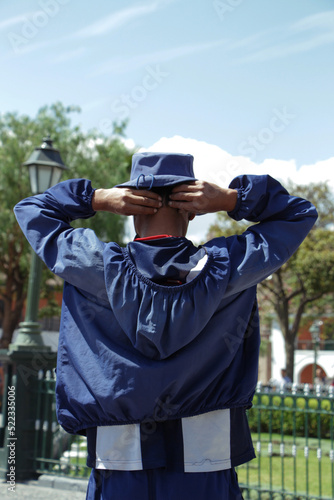 Persona dando la espalda con buzo azul y gorra azul.