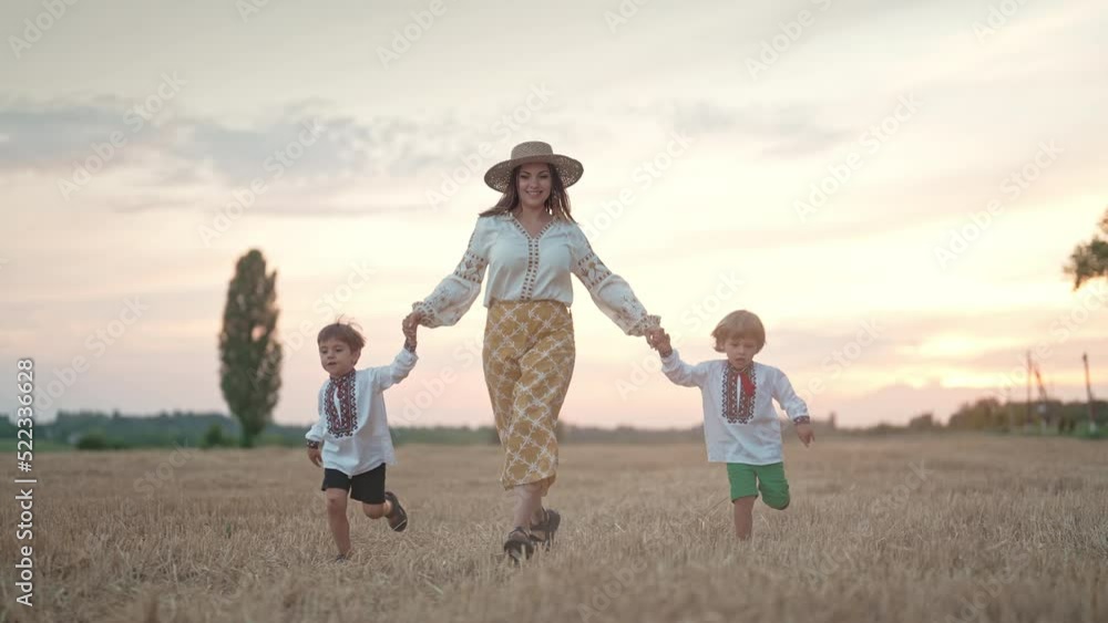 Two ukrainian boys and mother running together on open area wheat field after harvesting. Family friends holding hands. Children is our future. Nature background. Happy childhood. Two ukrainian boys and mother running together on open area wheat field after harvesting. Family friends holding hands. Children is our future. Nature background. Happy childhood.