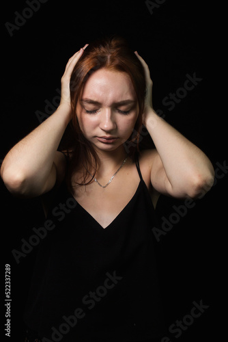 The girl covers her ears with her hands on a brown background. Social fatigue and desire to be alone