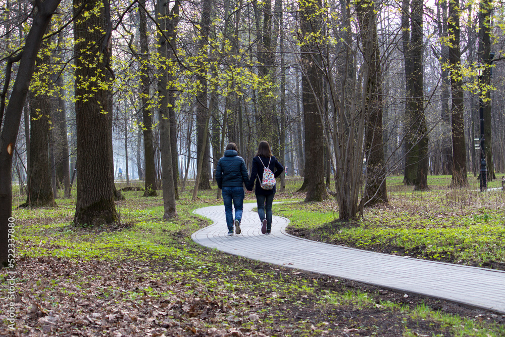Two girls are walking along a winding path in the park. Two girls are walking along a winding path in the park.