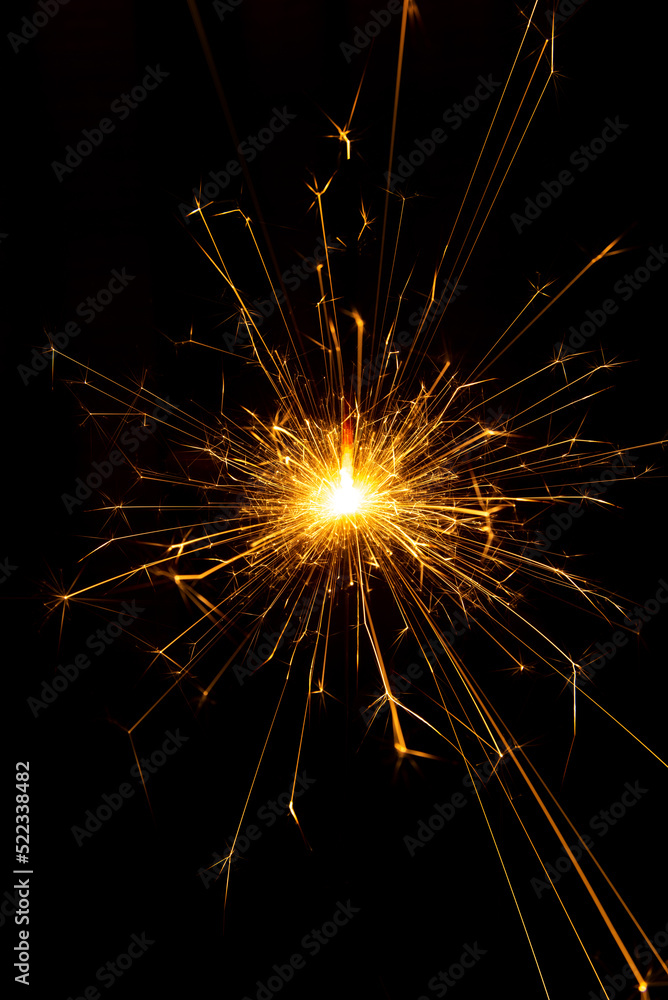 Sparkler candle used in celebrations, black background, selective focus.