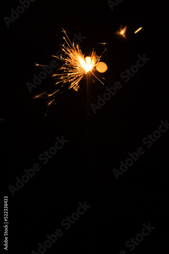 Sparkler candle used in celebrations, black background, selective focus.