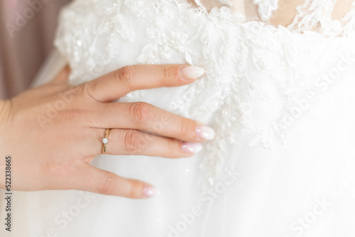 Cropped photo of woman touching white wedding embroidered dress with tender floral patterns with hand with white nails.