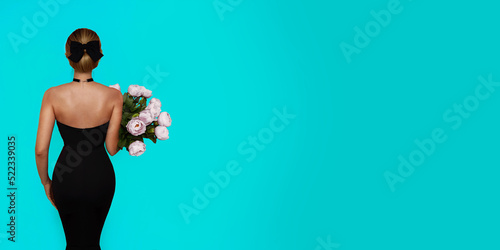 Photos A girl in a tight black dress standing with her back and holding a bouquet of peonies on a tiffany blue background