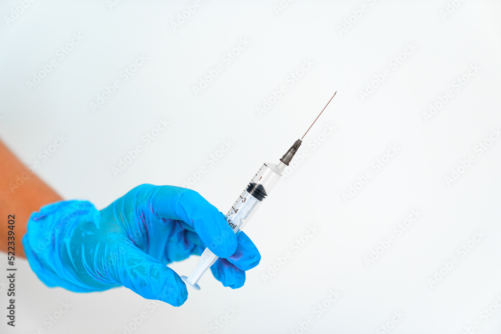 women's hands in blue gloves with a disposable syringe. women's hands in blue gloves with a disposable syringe.