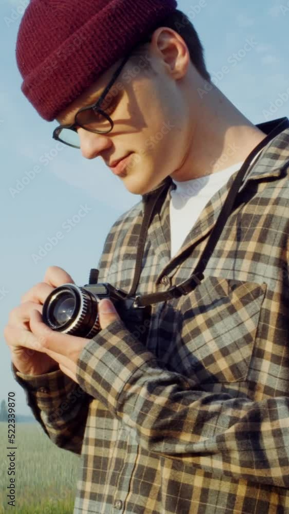 A young man takes photographs with a camera, capturing an agricultural landscape A young man takes photographs with a camera, capturing an agricultural landscape