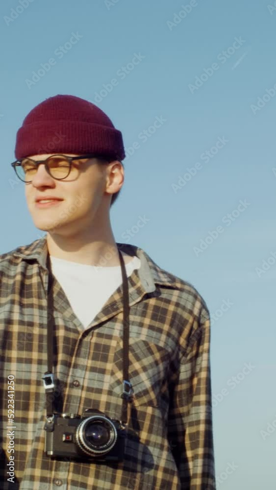 A man with a camera stands near a picturesque agricultural field A man with a camera stands near a picturesque agricultural field