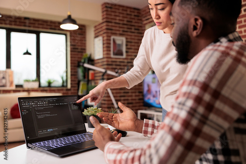 Programmers couple coding security firewall on laptop, using html and temrinal window to develop new user interface. Learnign to program software using cloud computing app server. photo