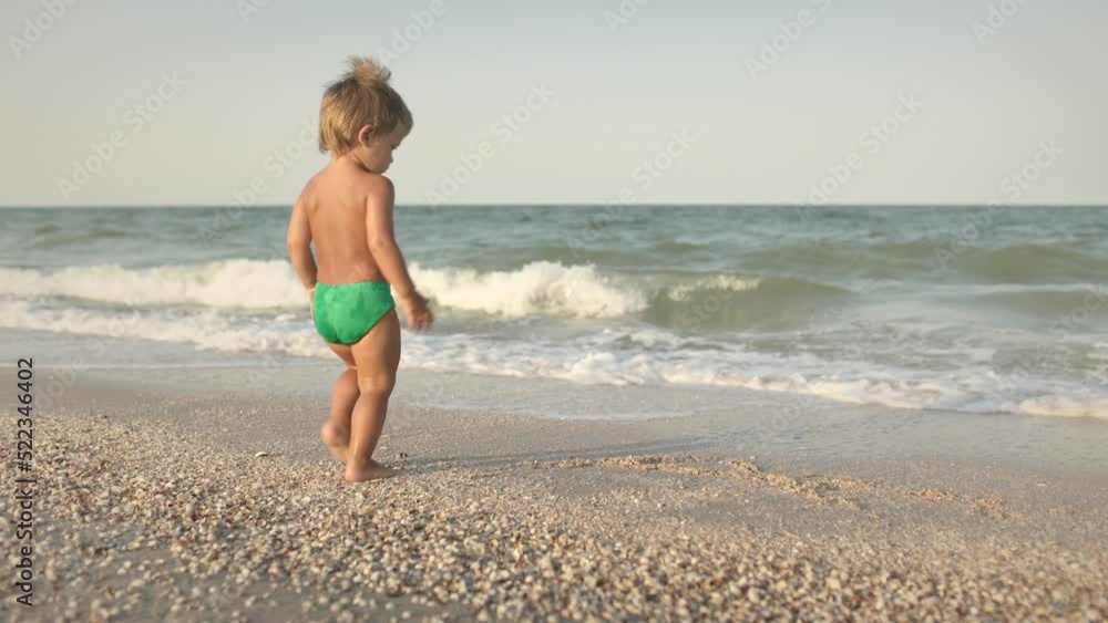 Kid collects shells and pebbles in the sea on a sandy bottom under the summer sun on a vacation Kid collects shells and pebbles in the sea on a sandy bottom under the summer sun on a vacation