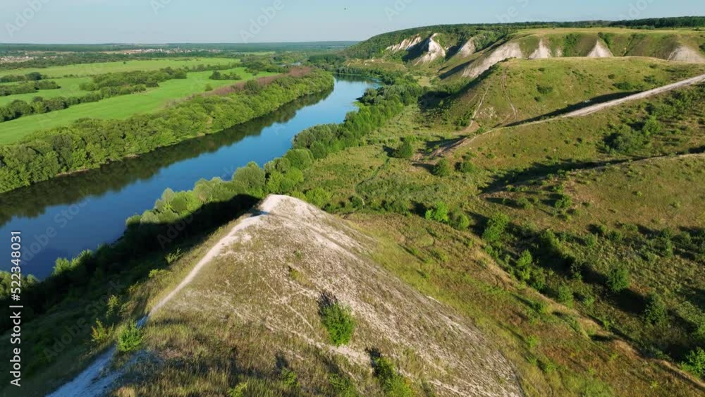 Flight over green hills, fields and white road on a sunny day. Chalk mountain. Blue sky. Aerial video drone footage. Flight over green hills, fields and white road on a sunny day. Chalk mountain. Blue sky. Aerial video drone footage.