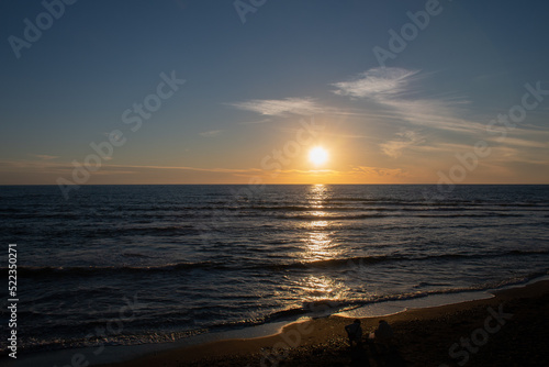 水平線に沈む夕陽と砂浜で遊ぶ人 