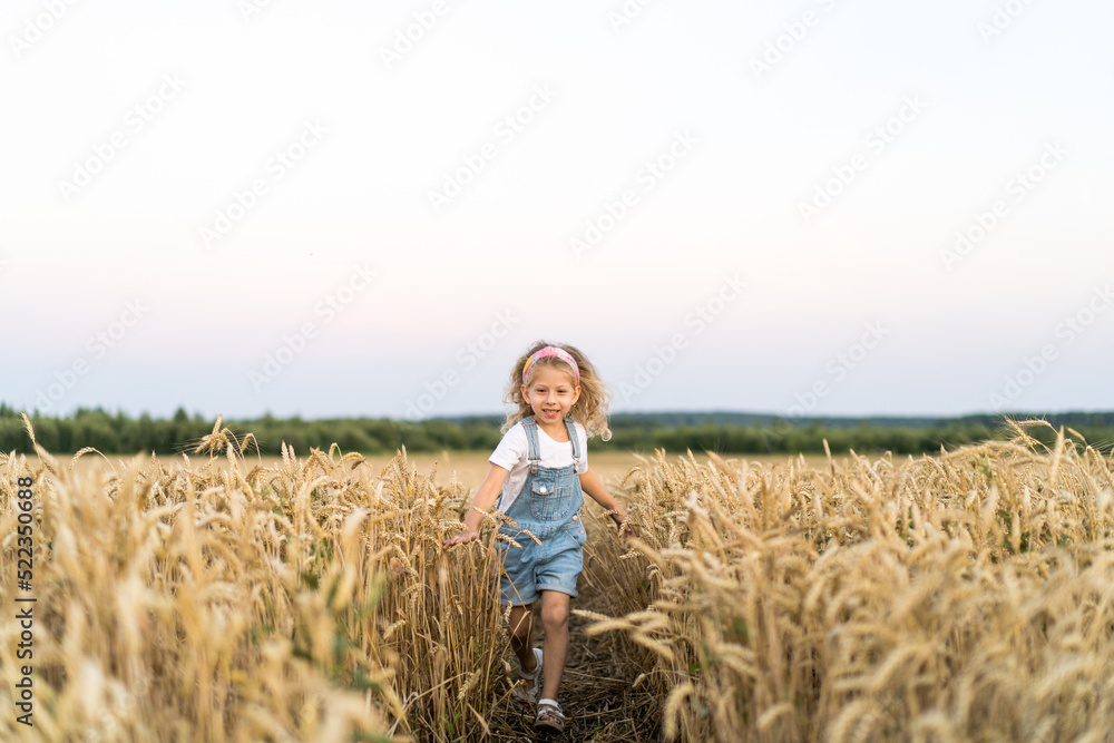 a little blonde curly girl running in a wheat field, the concept of human freedom a little blonde curly girl running in a wheat field, the concept of human freedom