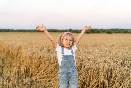 a little blonde curly girl running in a wheat field, the concept of human freedom © Надежда Урюпина