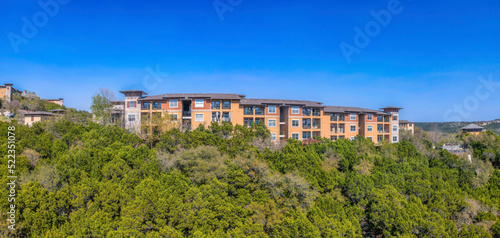 Austin, Texas- Apartment buildings near the cliff of a mountain with trees on the slope © Jason