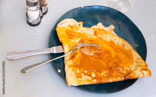 Just cooked crepe with salted butter caramel served on plate with serving pieces. photo