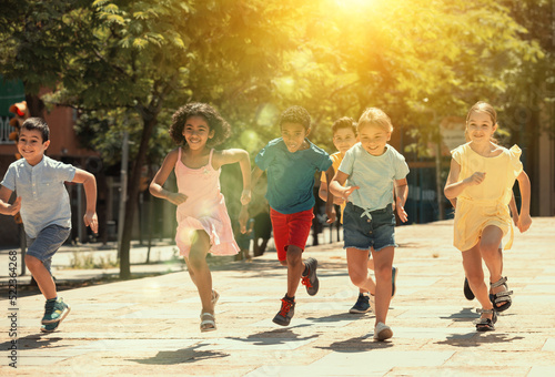 Group of joyful children running down the summer city street