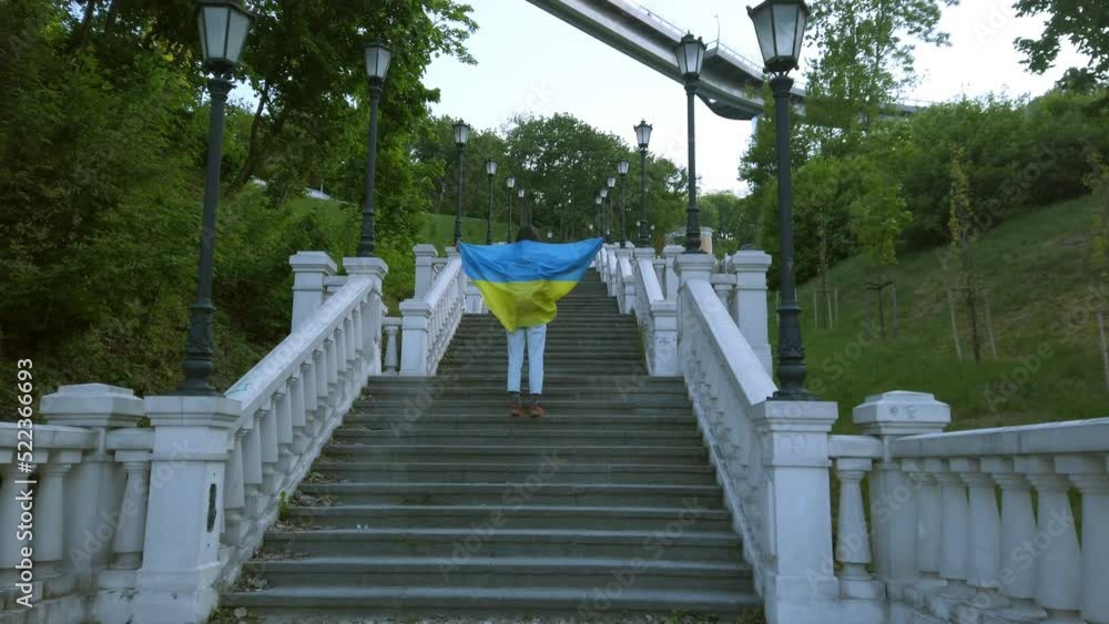 kyiv, ukraine 17 august 2022 young confident ukrainian woman walking up stairs holding national flag of ukraine. support ukraine, stand with ukraine kyiv, ukraine 17 august 2022 young confident ukrainian woman walking up stairs holding national flag of ukraine. support ukraine, stand with ukraine