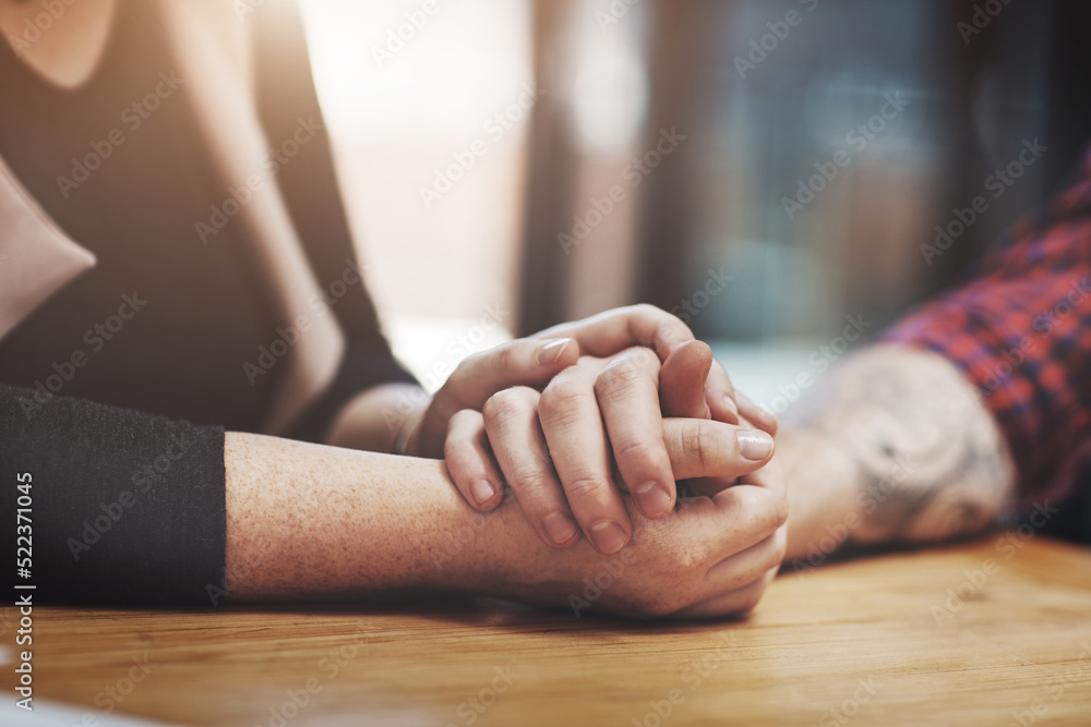 Support, compassion and trust while holding hands and sitting together at a table. Closeup of a loving, caring and affectionate couple comforting and helping each other through a difficult time