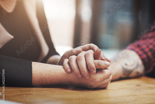 Support, compassion and trust while holding hands and sitting together at a table. Closeup of a loving, caring and affectionate couple comforting and helping each other through a difficult time © Nola Viglietti/peopleimages.com
