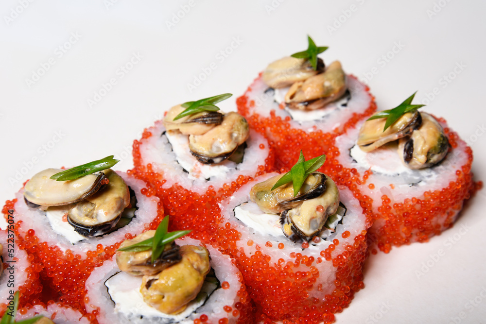 Elite sushi on a white background in red tobiko caviar with mussels on top. Food Elite sushi on a white background in red tobiko caviar with mussels on top. Food